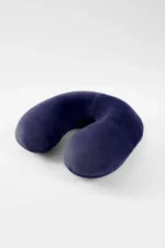 A navy Travel neck pillow with a U-shape rests on a white surface. It looks soft and comfortable, conveying a sense of relaxation and travel readiness.