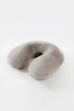 A Gray Travel neck pillow with a U-shape rests on a white surface. It looks soft and comfortable, conveying a sense of relaxation and travel readiness.