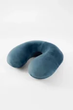 A Midnight Travel neck pillow with a U-shape rests on a white surface. It looks soft and comfortable, conveying a sense of relaxation and travel readiness.