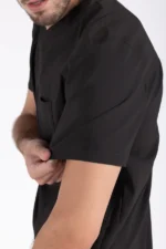 Man in black scrubs rolling up his sleeve, revealing a portion of his forearm. He appears focused, hinting at a professional or clinical setting.
