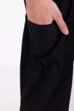 Close-up of a hand in a black pocket, showing part of the arm and pants. The background is white, giving a minimalist and modern feel.
