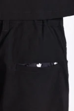 Close-up of black men's medical scrub pants with an elastic waistband. A small, subtle pocket is visible, slightly revealing a patterned fabric inside.