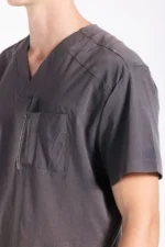 Close-up of a person wearing a gray scrub top with a V-neck and a chest pocket, showing a professional and clean appearance.