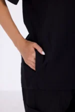 A close-up of a hand resting in the pocket of a black shirt, showcasing the garment's casual style and design.