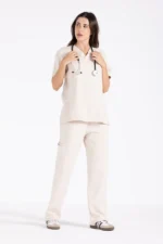A model stands confidently in a beige women medical Scrub top and matching pants, showcasing a stylish and comfortable outfit.