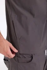 Close-up of a person wearing gray medical scrubs, focusing on the side pocket area. A hand gently holds the fabric, showcasing the pocket's design.