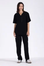 A model stands confidently in a black short-sleeve top and matching pants, showcasing a stylish and comfortable outfit.