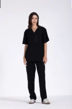 A model stands confidently in a black short-sleeve top and matching pants, showcasing a stylish and comfortable outfit.