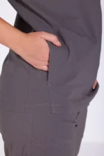 A person in gray scrubs inserts their hand into a side pocket, showcasing comfort and practicality. The focus is on the fabric and hand placement.
