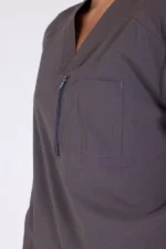A close-up of a person wearing a dark gray scrub top with a zippered chest pocket, emphasizing practical design and professional attire.